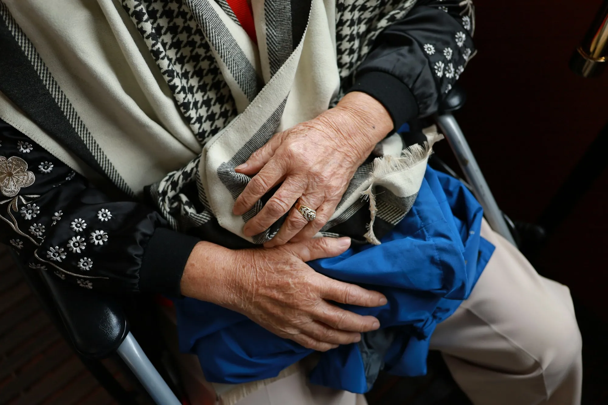 An older person's hands resting on a blanket