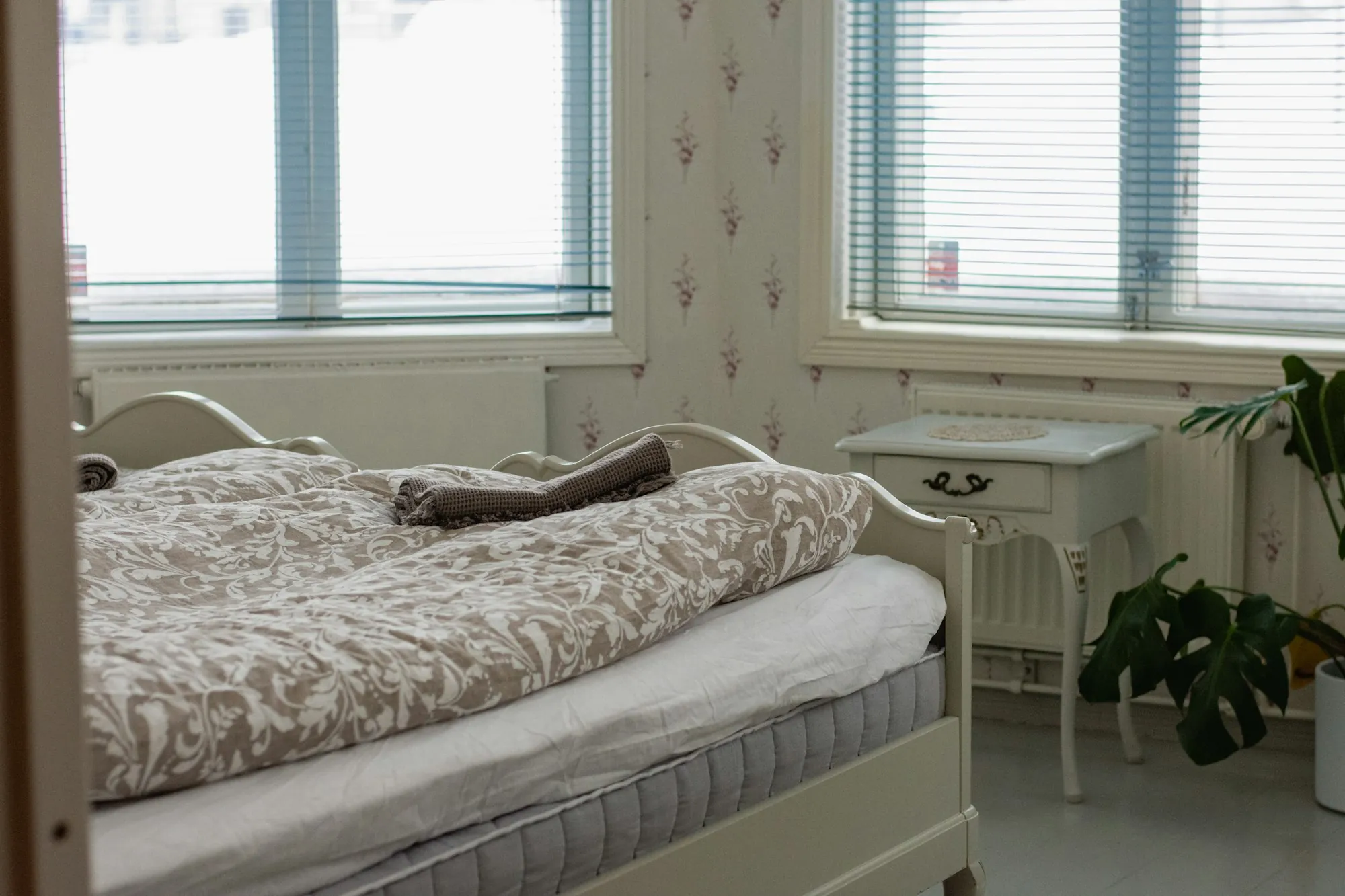 A made bed beside a window in a bright bedroom
